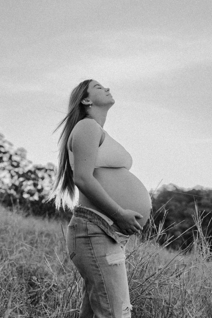 black and white of a pregnant woman holding a belly with her head back