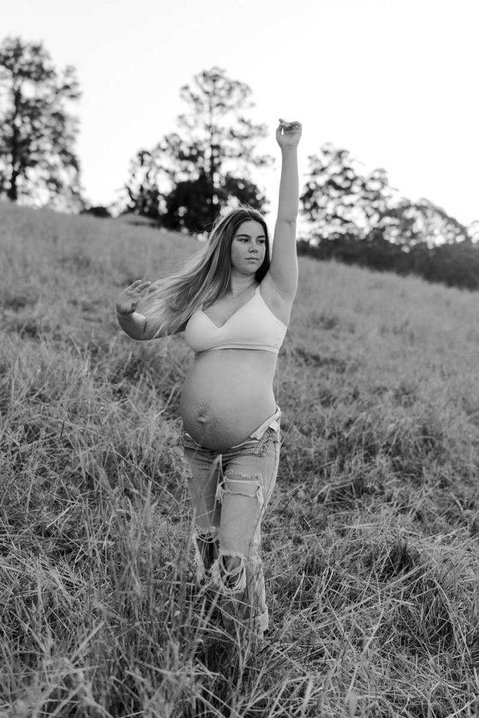 black and white image of a pregnant woman standing in a field