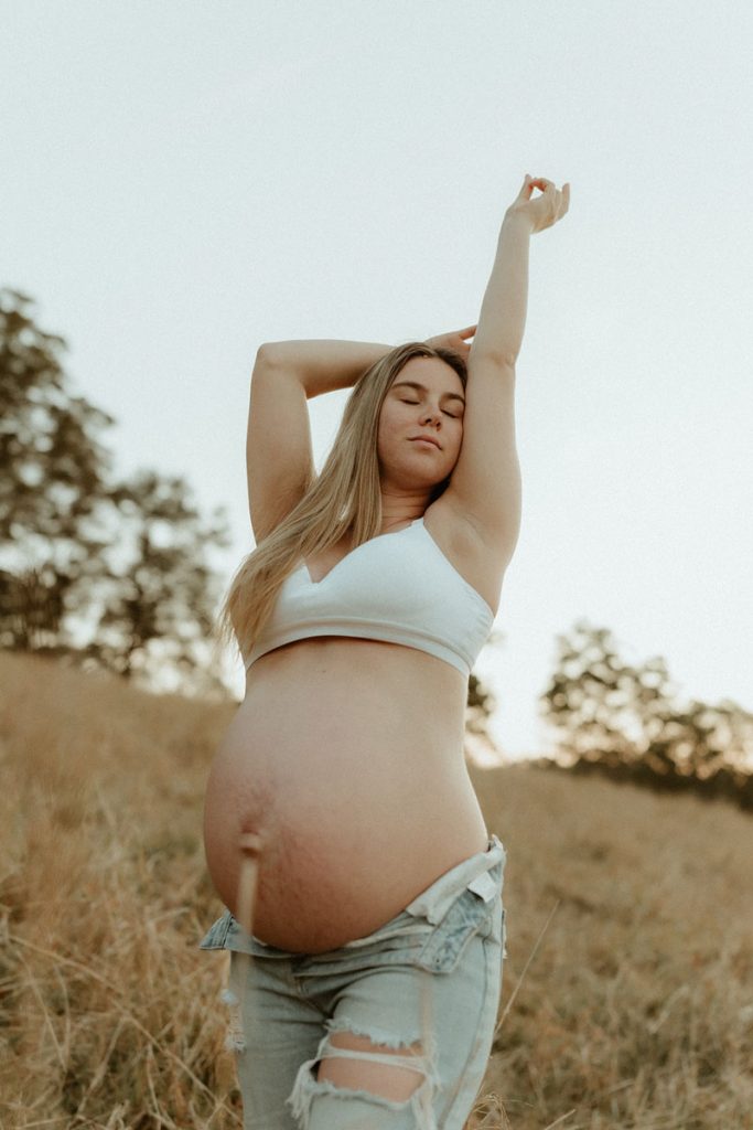pregnant yound woman standing in a field