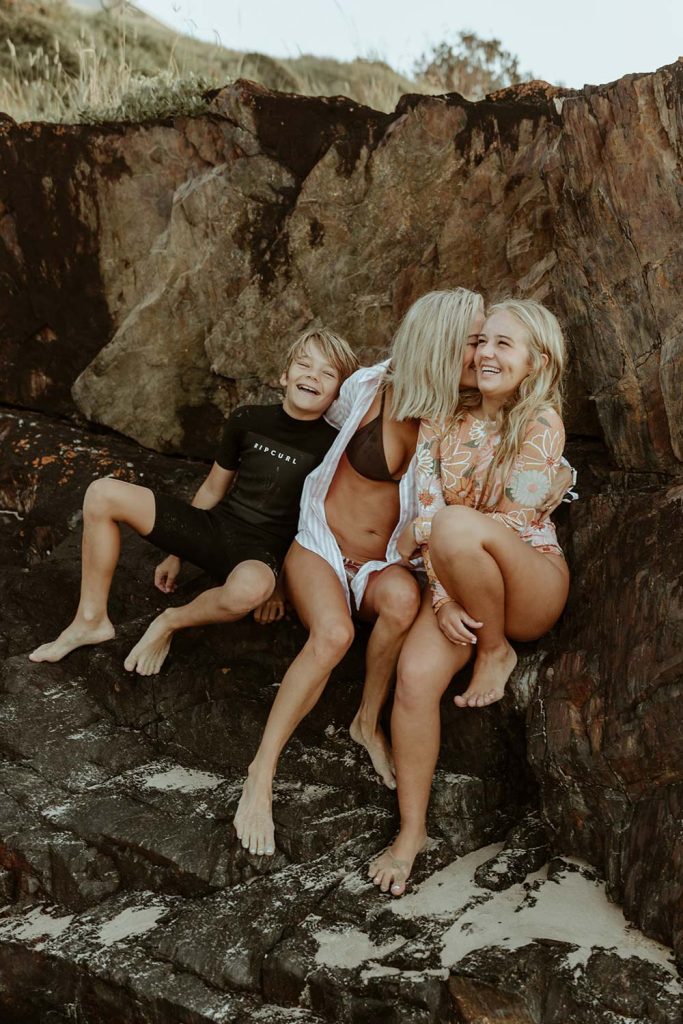 Mum and sitting on a rocks with her son and daughter cuddling and laughing