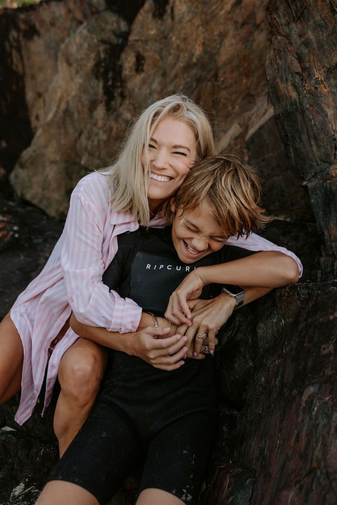 Mum and her son sitting on a rock  laughing together
