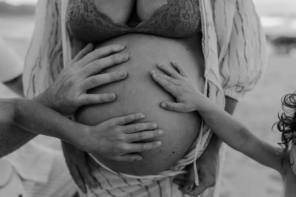 hands of dad and sons on mum's pregnant belly