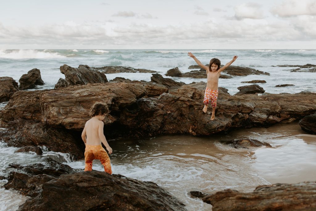 two brother jumping in a little rock pool at the beach